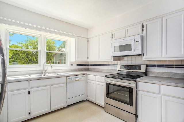 kitchen with decorative backsplash, white cabinetry, white appliances, and sink