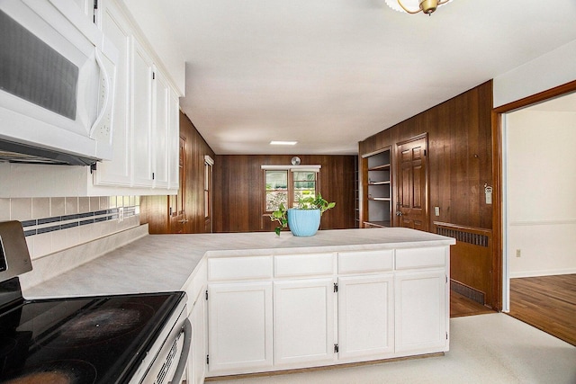 kitchen with white cabinetry, electric range, wood walls, and light wood-type flooring