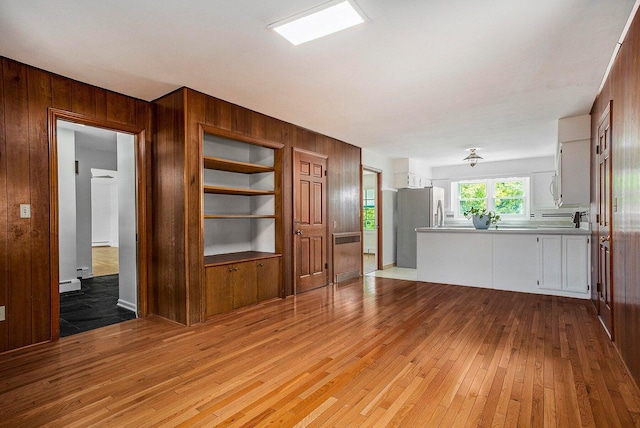 unfurnished living room with wood walls and light hardwood / wood-style floors