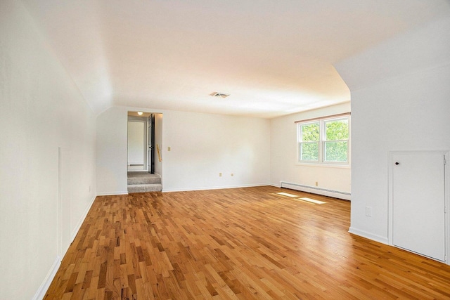 unfurnished living room featuring wood-type flooring and a baseboard heating unit