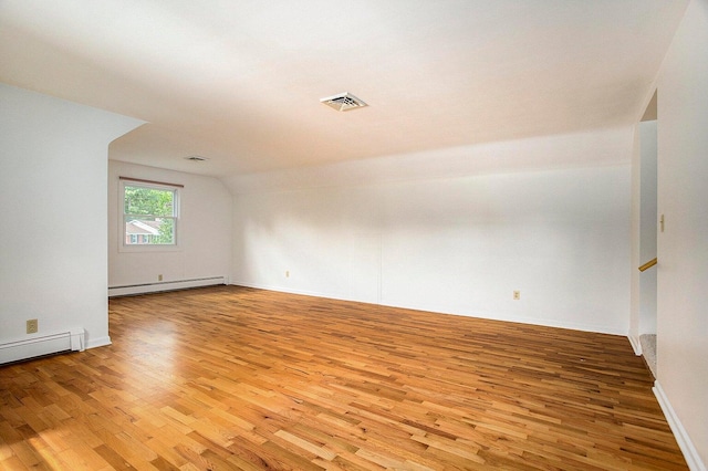 unfurnished room with hardwood / wood-style floors, lofted ceiling, and a baseboard radiator