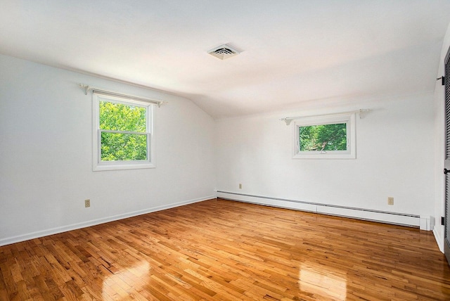 empty room featuring light wood-type flooring, lofted ceiling, and a baseboard radiator