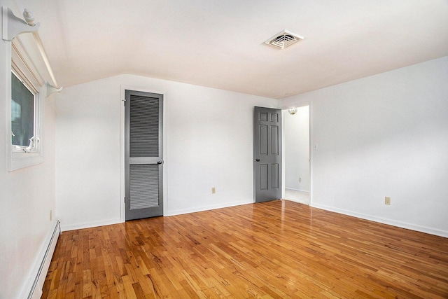 unfurnished bedroom featuring a baseboard radiator, lofted ceiling, and wood-type flooring