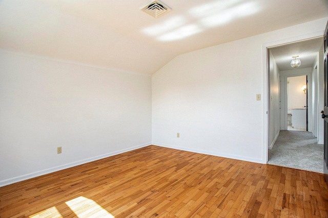 unfurnished room featuring lofted ceiling and light hardwood / wood-style flooring