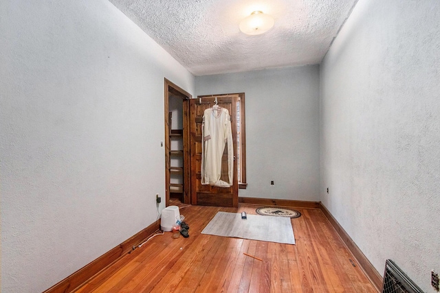 spare room with light hardwood / wood-style floors and a textured ceiling