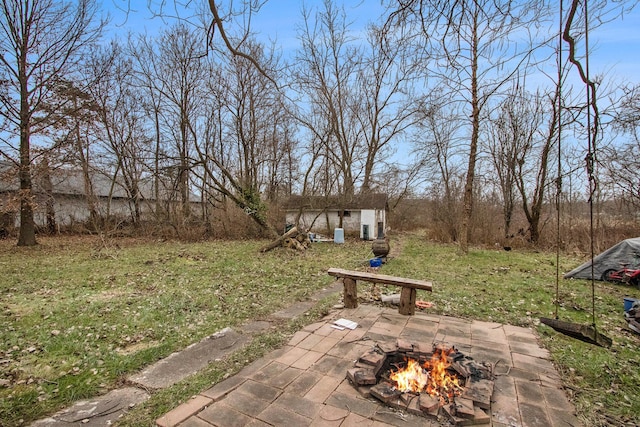 view of yard featuring a patio, a fire pit, and an outdoor structure