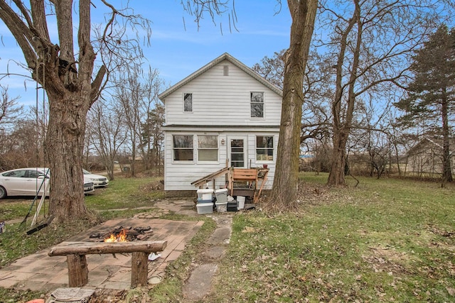 rear view of house with a lawn and a fire pit