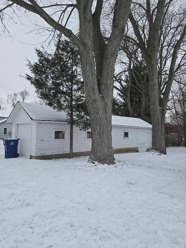 view of snowy exterior with a garage and an outdoor structure