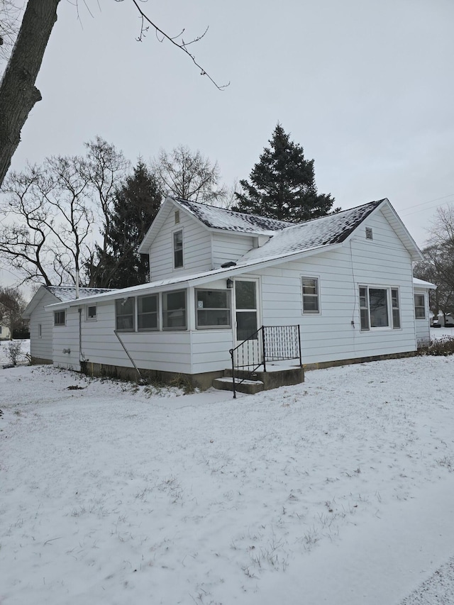 snow covered house with a sunroom