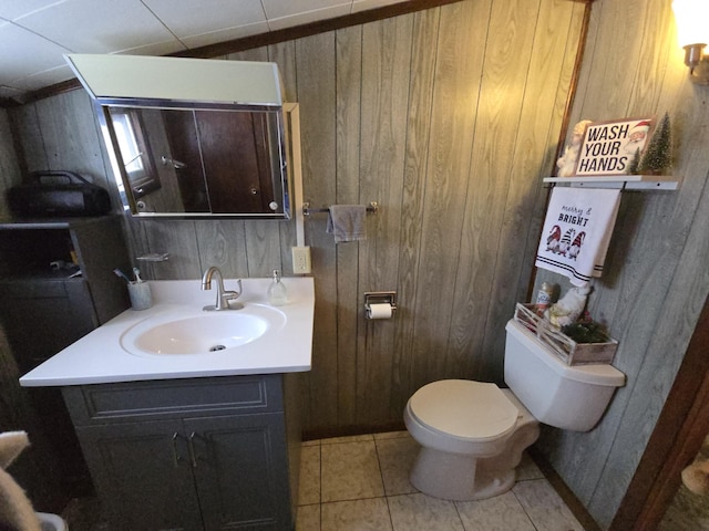 bathroom with tile patterned floors, wood walls, and vanity