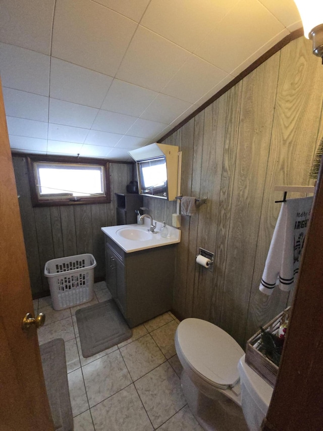 bathroom with tile patterned floors, wood walls, vanity, and toilet