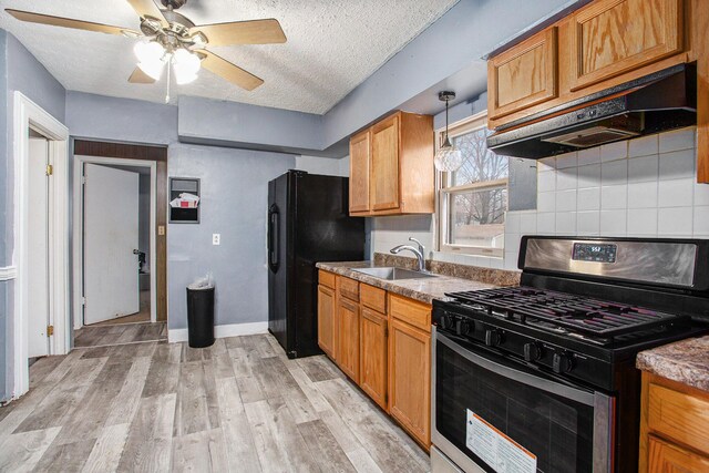 kitchen with stainless steel range with gas cooktop, sink, decorative backsplash, a textured ceiling, and light hardwood / wood-style floors