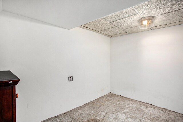 carpeted spare room featuring a drop ceiling