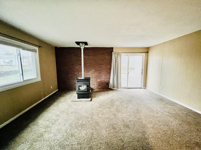 unfurnished living room featuring a wood stove and carpet floors