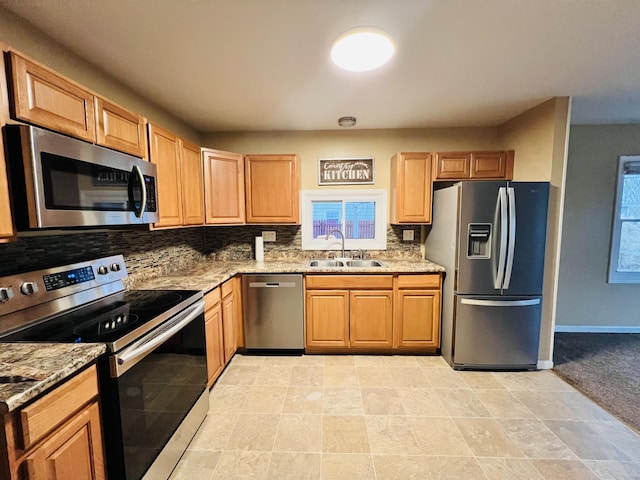 kitchen featuring light stone counters, sink, stainless steel appliances, and tasteful backsplash