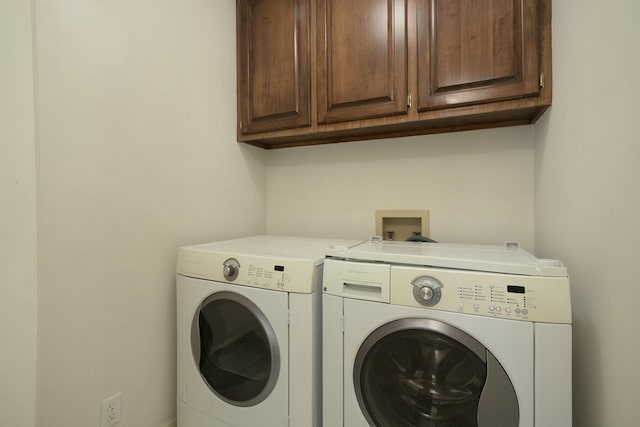 clothes washing area with washer and clothes dryer and cabinets