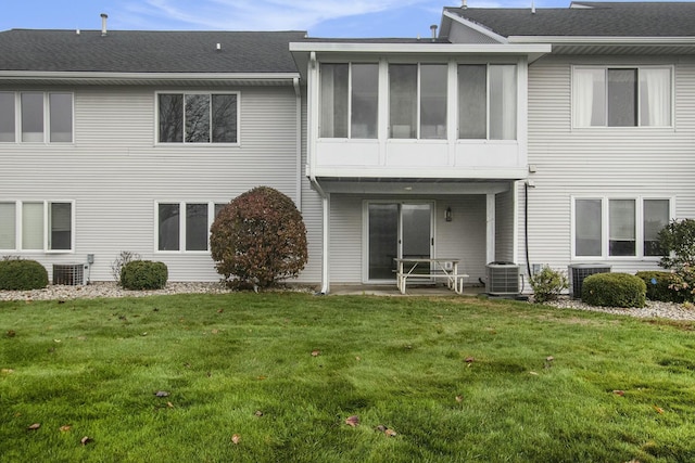 back of house featuring central AC unit, a sunroom, and a lawn