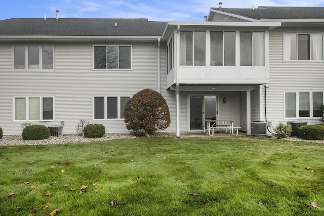 rear view of house featuring central air condition unit, a patio area, a sunroom, and a yard