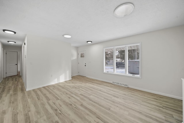 unfurnished room featuring a textured ceiling and light hardwood / wood-style flooring