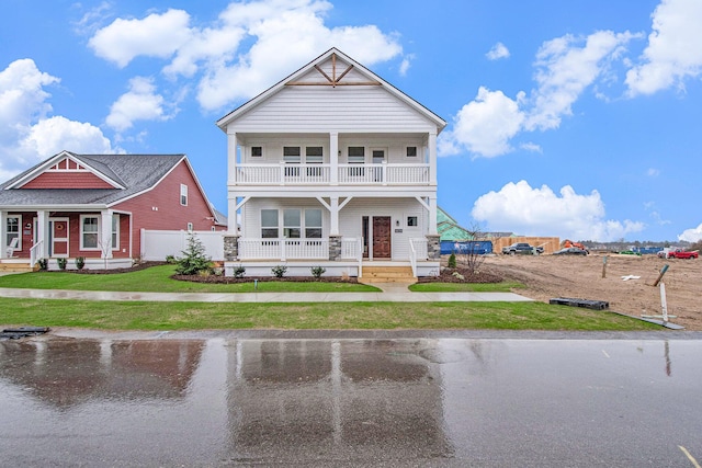 view of front of house featuring a porch, a balcony, and a front yard