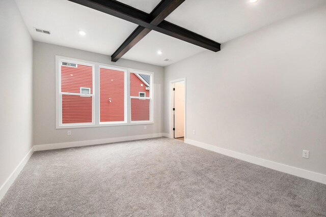 empty room with beam ceiling and light carpet