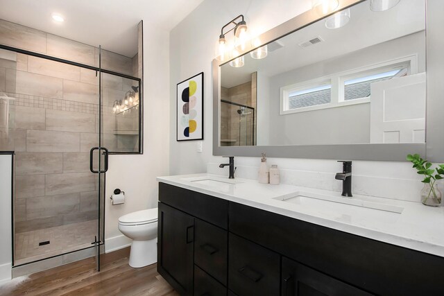 bathroom with vanity, toilet, wood-type flooring, and a shower with door