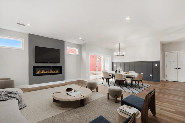 living room with light hardwood / wood-style floors and an inviting chandelier