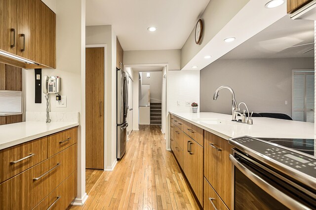 kitchen featuring recessed lighting, light wood finished floors, light countertops, a sink, and appliances with stainless steel finishes