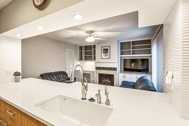 kitchen with recessed lighting, a sink, brown cabinetry, open floor plan, and ceiling fan
