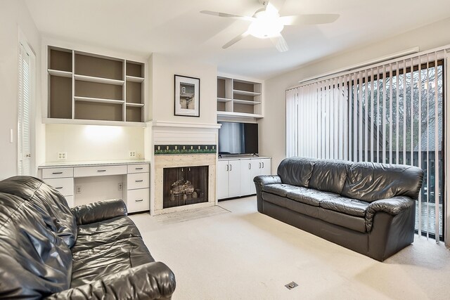 living room featuring a fireplace, carpet floors, and a ceiling fan