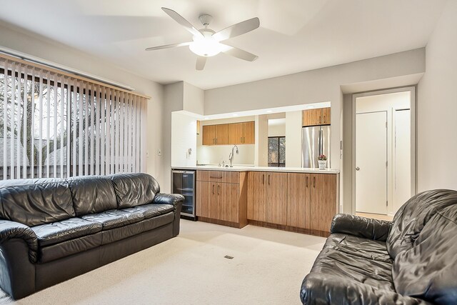 living room with wine cooler, light colored carpet, a ceiling fan, and wet bar