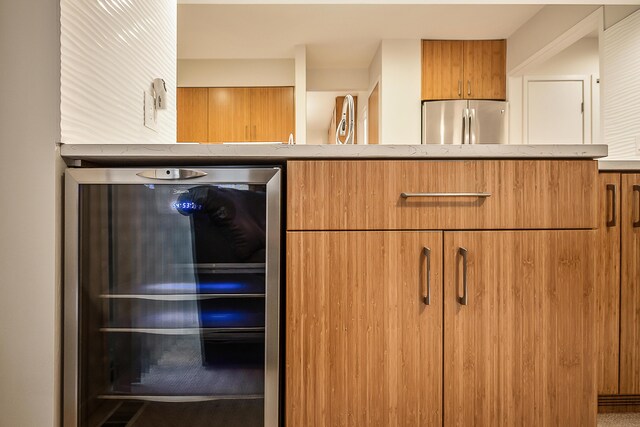 details with brown cabinetry, beverage cooler, and freestanding refrigerator