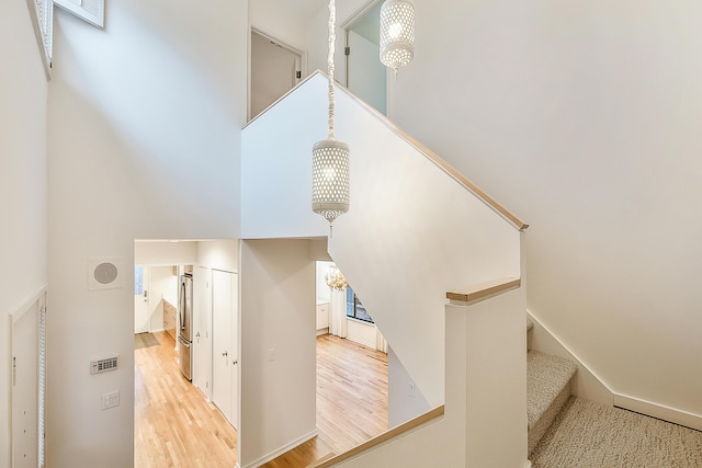 stairs featuring visible vents, a towering ceiling, and wood finished floors