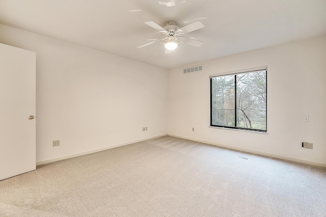 empty room featuring ceiling fan, visible vents, baseboards, and light carpet