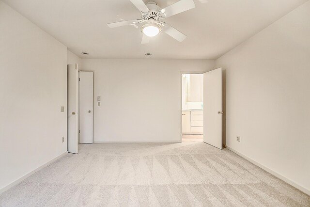empty room featuring light carpet, a ceiling fan, and baseboards