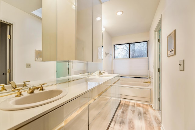 full bathroom featuring a garden tub, wood finished floors, a sink, and double vanity
