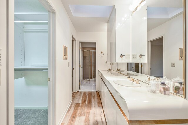 full bath featuring double vanity, a shower stall, wood finished floors, and a sink