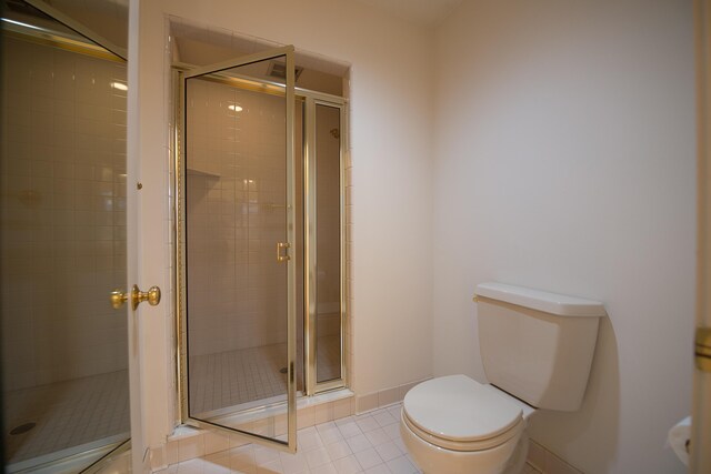 bathroom with tile patterned flooring, baseboards, toilet, and a stall shower