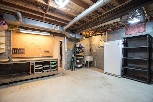 unfinished below grade area with freestanding refrigerator, a sink, and a workshop area