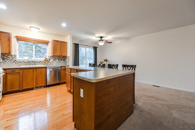 kitchen featuring dishwasher, a healthy amount of sunlight, a kitchen island, and light wood-type flooring