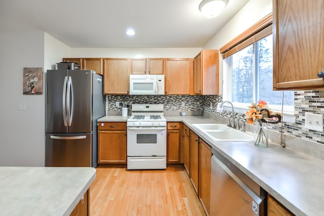 kitchen featuring backsplash, light wood-type flooring, sink, and appliances with stainless steel finishes