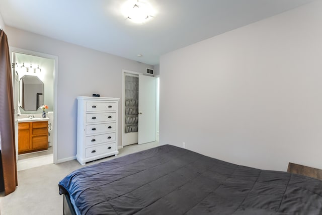 carpeted bedroom featuring ensuite bathroom and sink