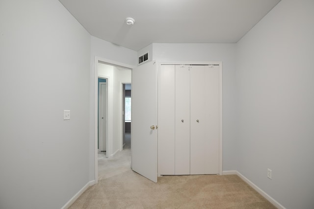 unfurnished bedroom featuring light carpet and a closet