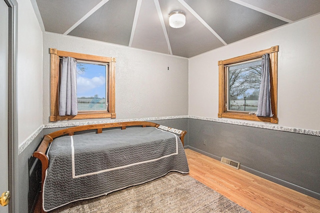 bedroom with hardwood / wood-style flooring, vaulted ceiling, and multiple windows