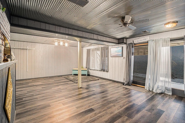 empty room featuring wooden walls, ceiling fan, and wood-type flooring