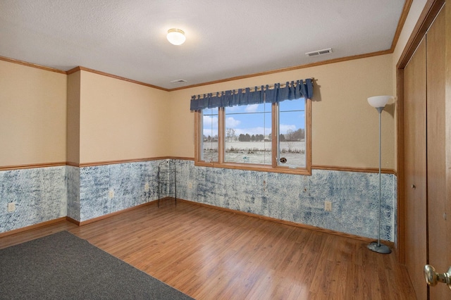 unfurnished room with hardwood / wood-style floors, ornamental molding, and a textured ceiling