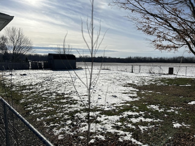 snowy yard featuring a rural view and a storage unit