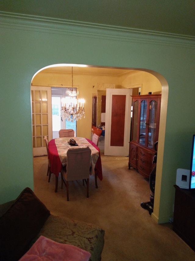 dining space featuring carpet, a notable chandelier, crown molding, and french doors