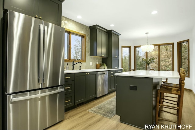 kitchen with a wealth of natural light, a center island, hanging light fixtures, and appliances with stainless steel finishes