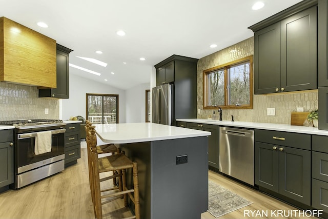 kitchen featuring appliances with stainless steel finishes, lofted ceiling with skylight, a wealth of natural light, and a kitchen island